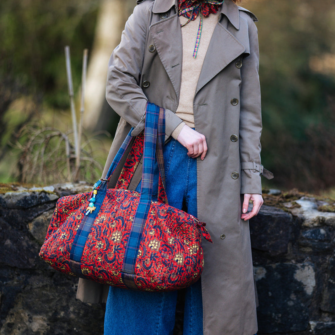 Woman holding a colorful bag outdoors with a blurred natural background