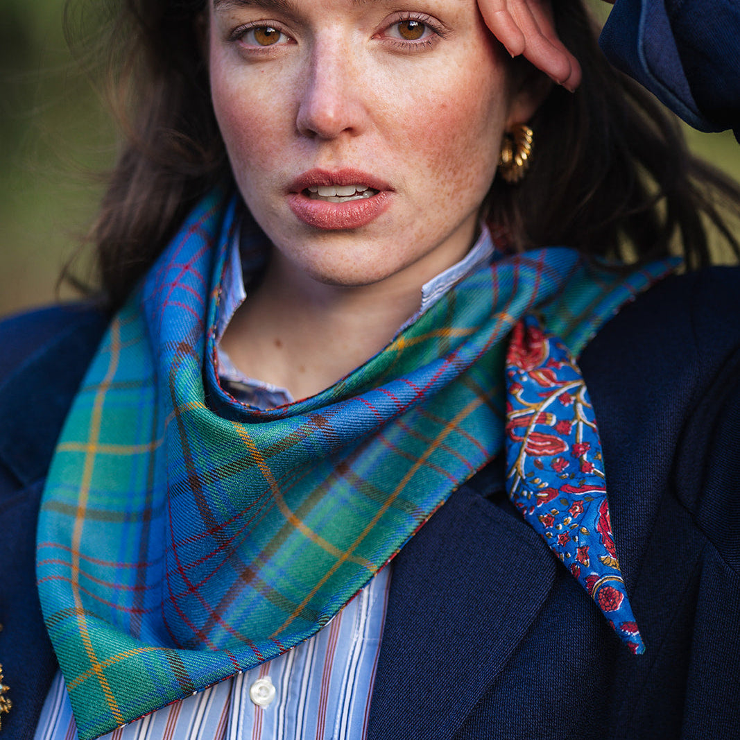 Woman wearing a green donegal tartan plaid scarf with blockprint and gold hoops
